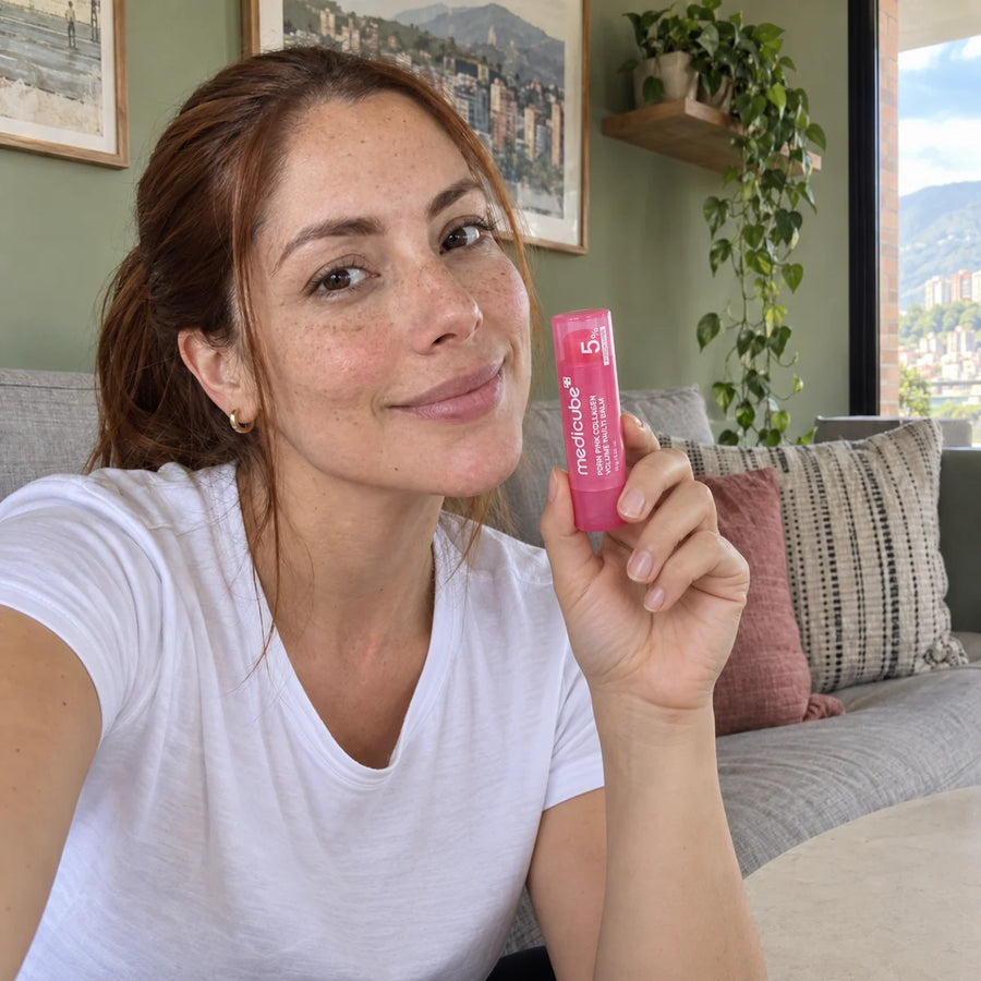 Mujer sentada en casa sosteniendo el bálsamo de forma natural.