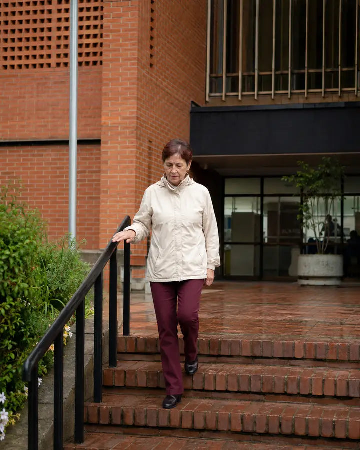 Mujer mayor bajando escalones exteriores con cuidado