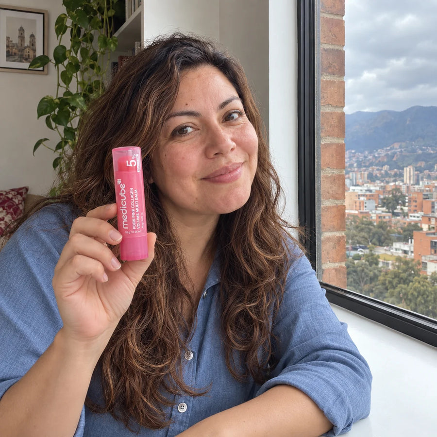 Mujer junto a una ventana sosteniendo el bálsamo de forma natural.